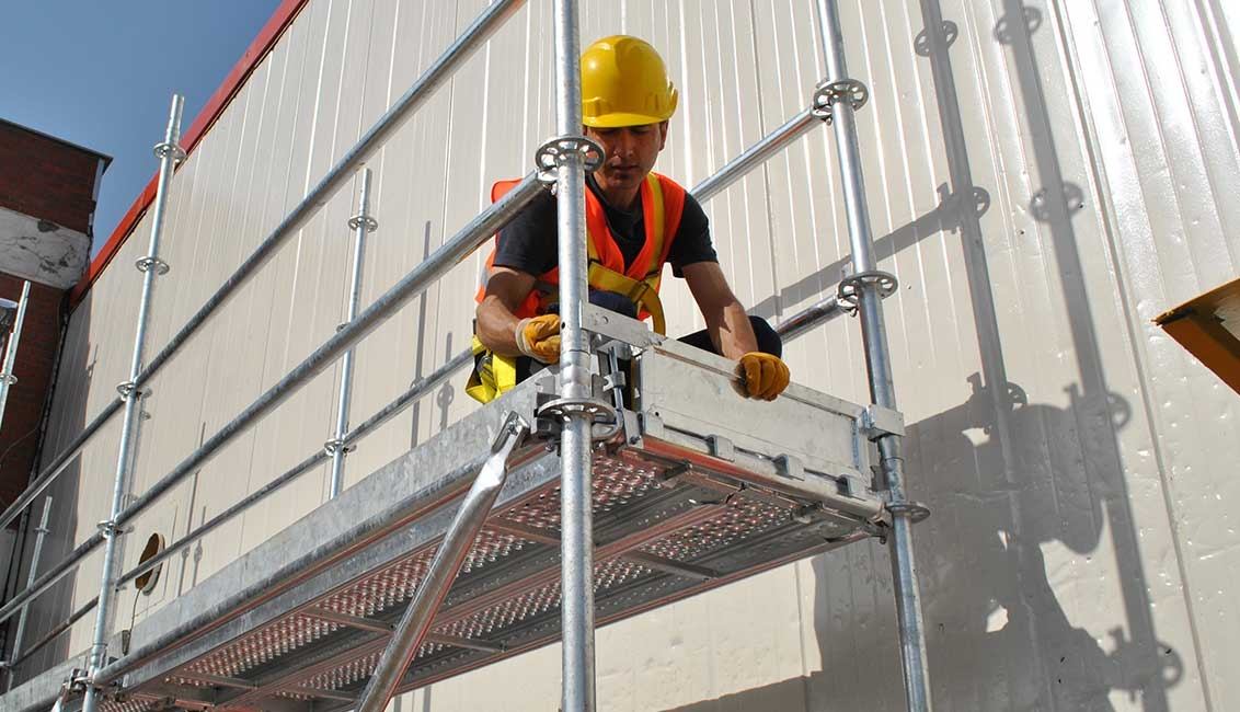 Flanşlı galvaniz cephe iskelesi üzerinde çalışan işçi