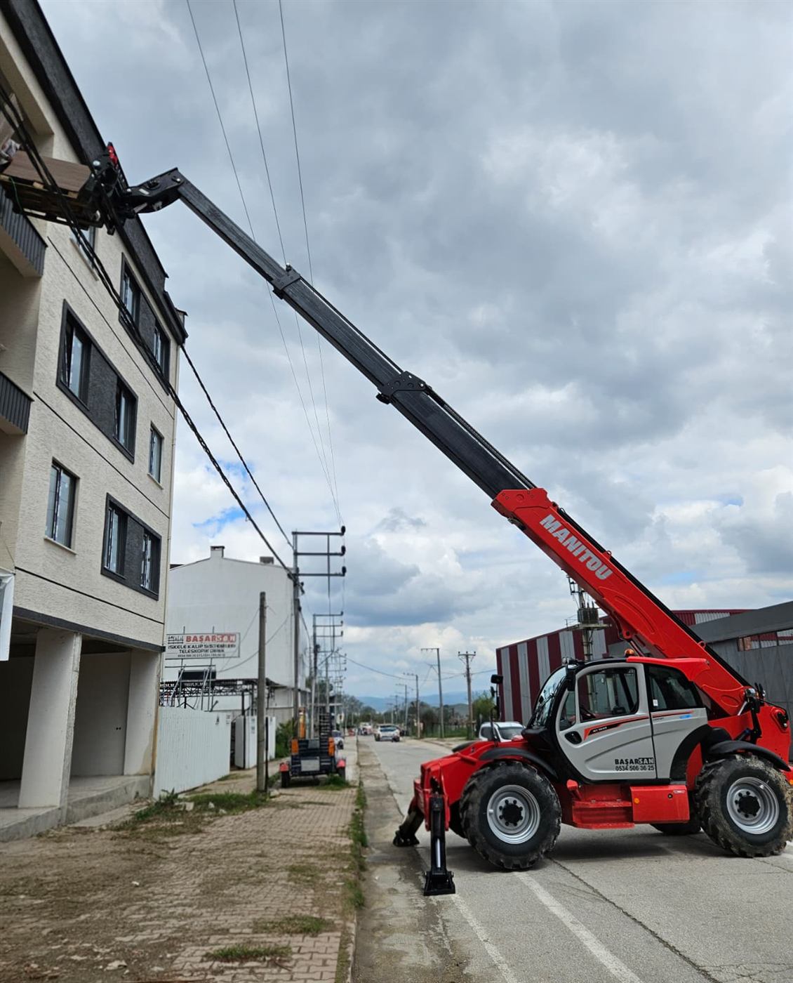 Manitou teleskopik yükleyici ile binaya malzeme çıkarılması